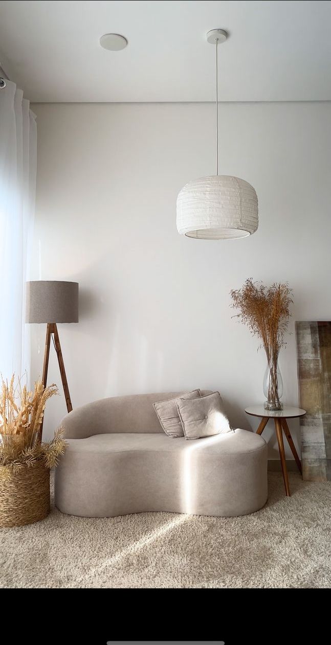 Cenário sofá, com sofá orgânico bege, abajur de tripé, luminária pendente e vaso com capim seco