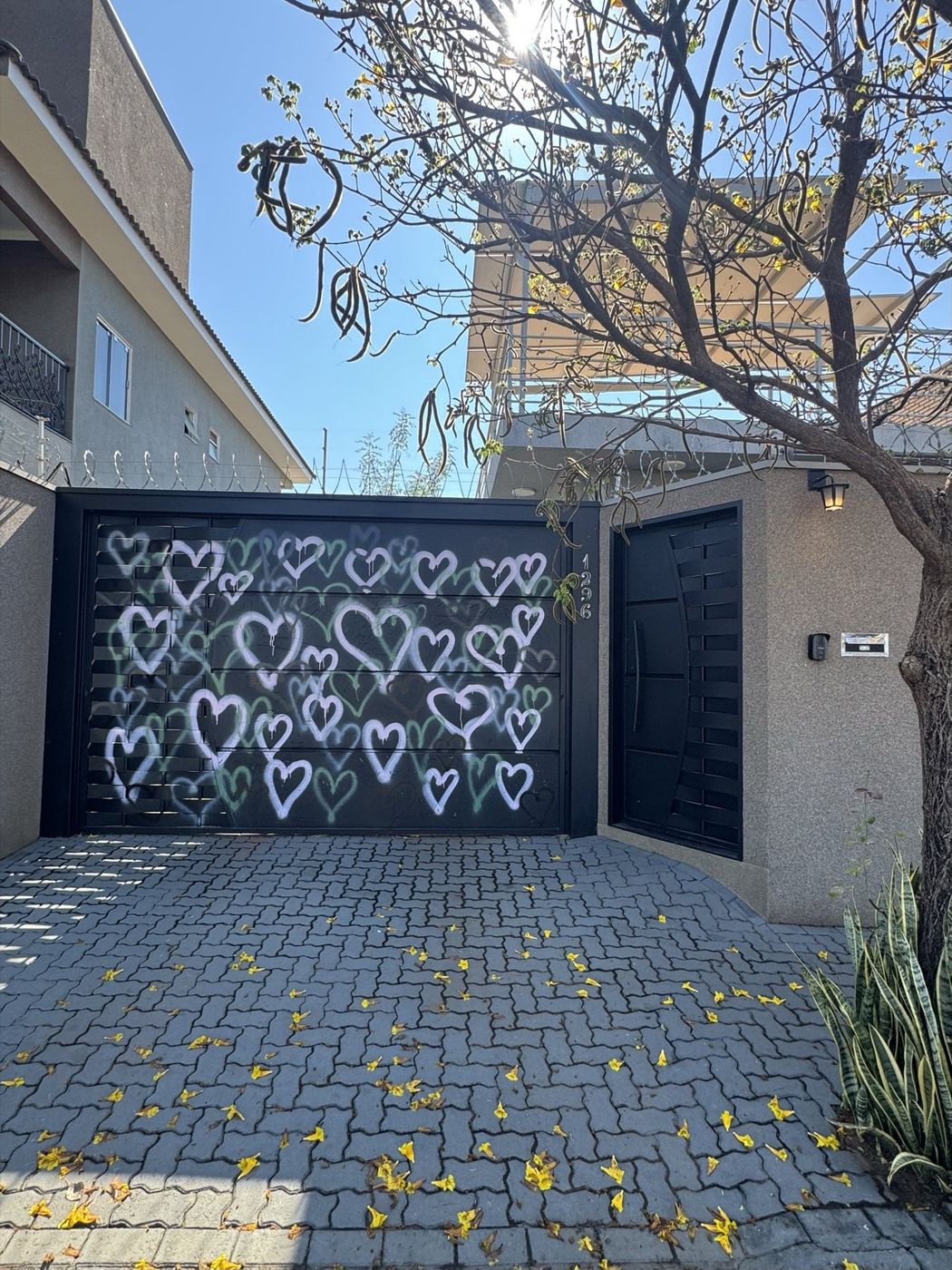 Fachada do estúdio: portão preto grafitado com corações brancos, número 1296